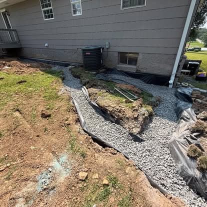 Gravel pathway under construction beside a house with landscaping fabric and dirt excavation.