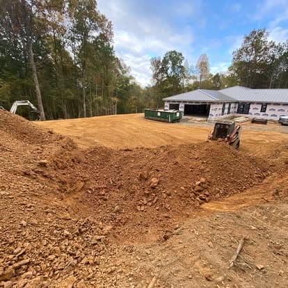 Construction site with excavated dirt and machinery near a building in progress.