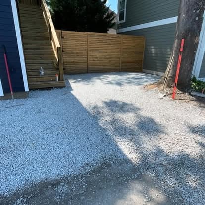 Gravel driveway next to stairs and wooden gate, enhancing outdoor space appeal.