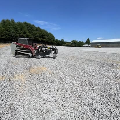 Gravel leveling equipment on a newly gravelled construction site under a clear blue sky.