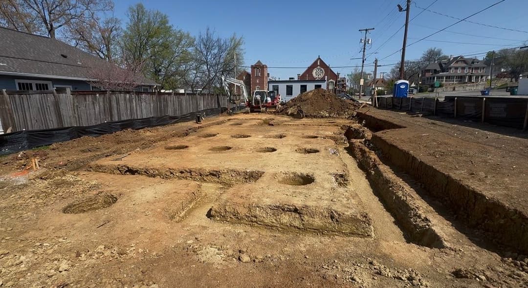 Excavation site with foundation holes for construction in a residential area.