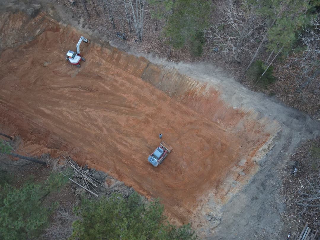 Aerial view of a construction site with earthmoving equipment and cleared land.